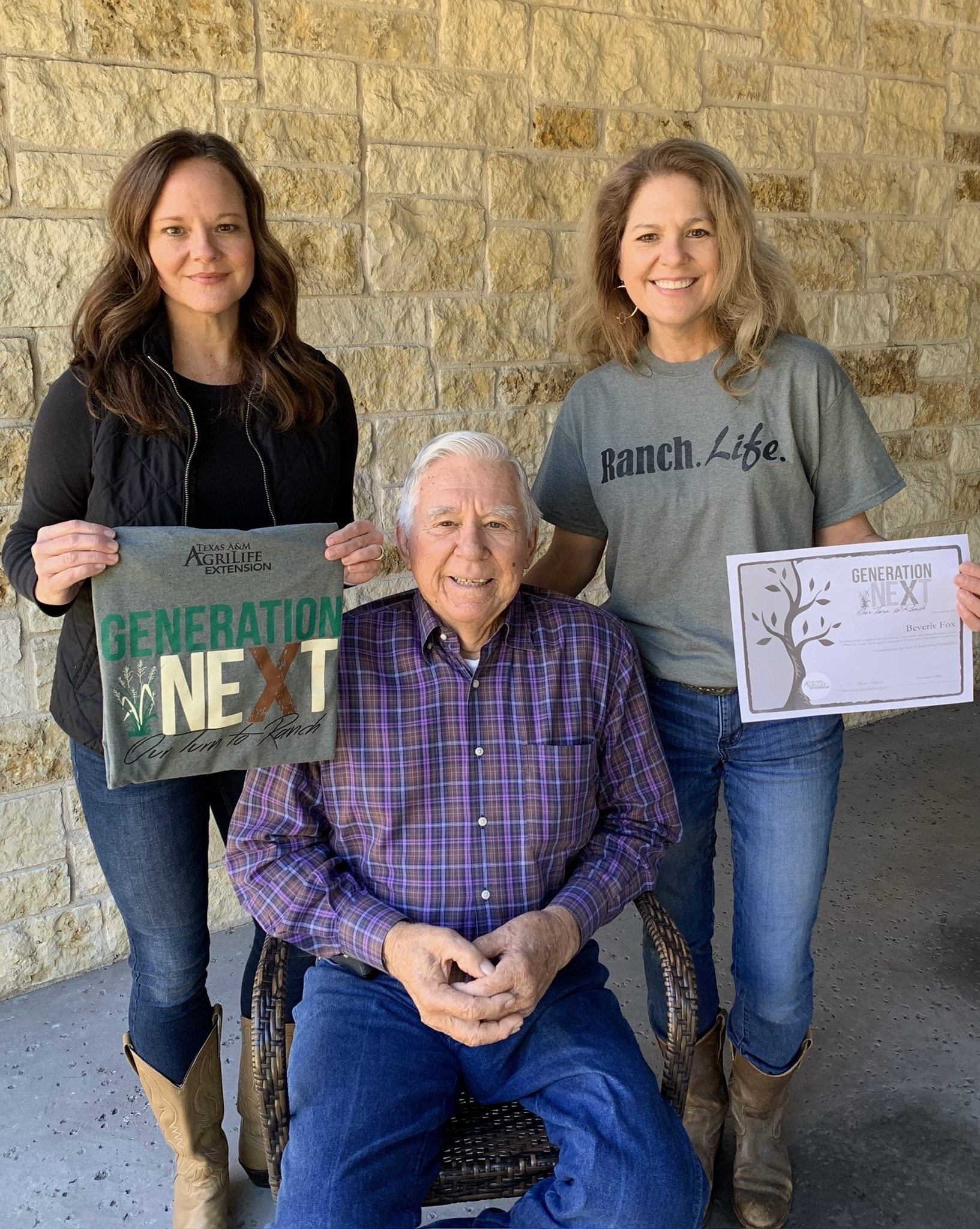 Two Generation Next graduates holding their course certificates while standing next to their father at their ranch.